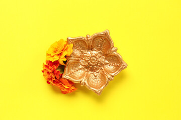 Diya lamp with marigold flowers on yellow background. Divaly celebration