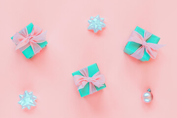 Three green present boxes with bow on pink background with Christmas balls and baubles. Holidays concept. Top view, flat lay