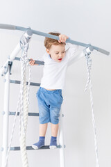 a child a boy does sports or exercises on the Swedish wall of the house