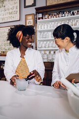 Interracial apothecary workers are making the cure together at a vintage apothecary.