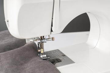Modern sewing machine with gray fabric. Sewing process clothes, curtains upholstery. Business, hobby, handmade, zero waste, recycling, repair concept
