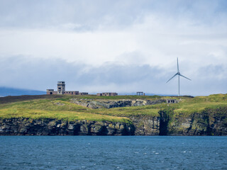 Old wartime coastal defense bunkers beside modern wind turbine on the shore of Orkney, Scotland