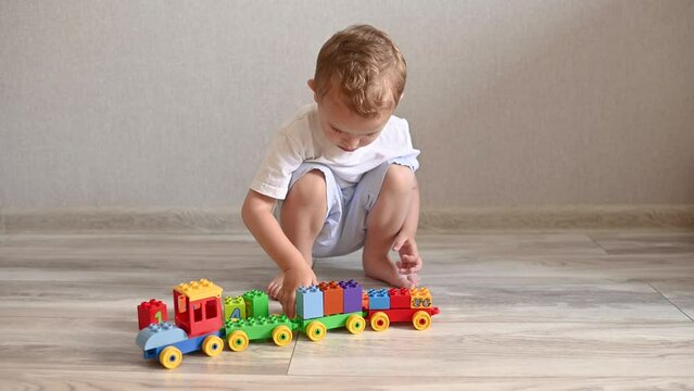 the kid is playing a train with trailers from the constructor with cubes with numbers. Leisure and education of the child