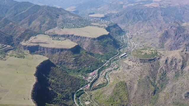 Forward reveal aerial shot of Debed river gorge and plateaus above it on sunny summer day. Lori Province, Armenia.