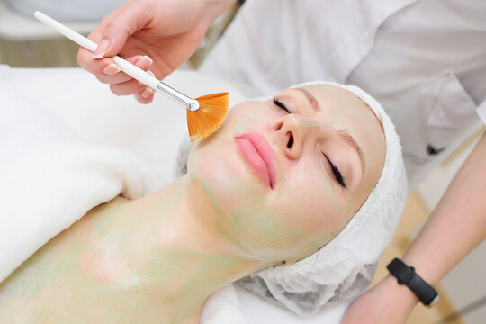 A cosmetologist performs an enzyme therapy procedure for a female patient.