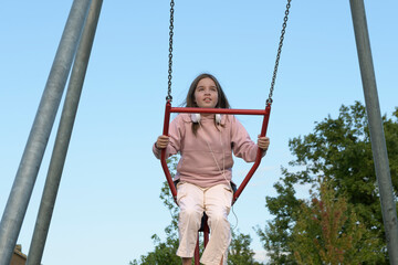 A teenage girl swings on a swing. Fun childhood time