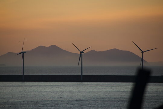 Atardecer en el mar con molino eolico