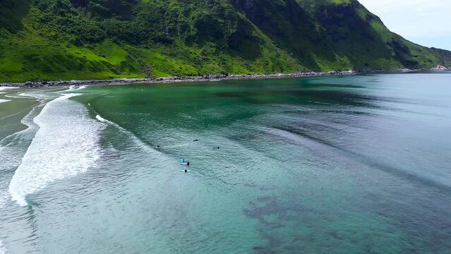 Scenic ocean landscape. Surfers padling in the waves in the beautiful turquoise water. Hoddevika, Norway. 