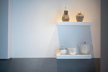 Some white pots and crockery on white shelfs in a modern interior kitchen fancy decor white wall