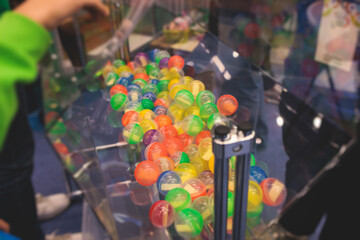 Process of prize drawings, extracting a winning numbers of lottery machine, raffle drum with a bingo balls, bingo machine and winning tickets on event with a host, hands on lottery machine