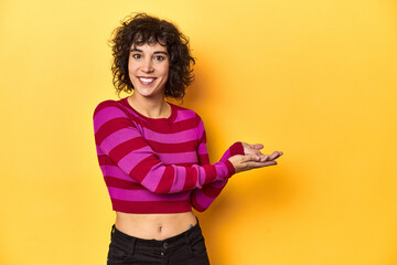 Caucasian curly-haired woman in pink striped-top holding a copy space on a palm.