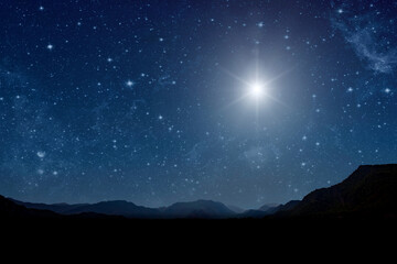 A christmas star shines at night over the mountains of Bethlehem