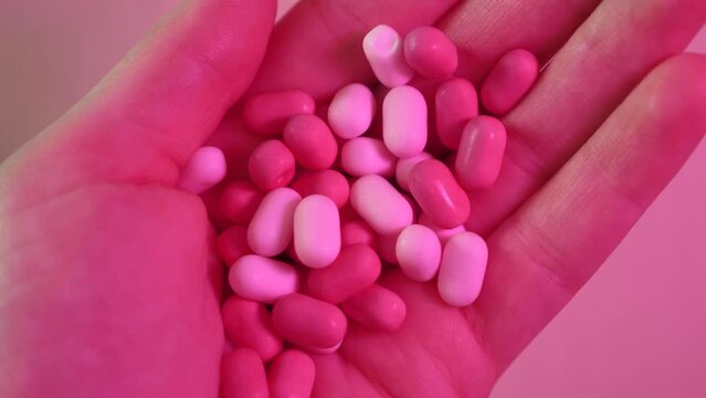 Sweets, candies, dragee pink tic tac in hand, summer 2023 trend. Barbie-style close-up, neon magenta professional studio lighting.