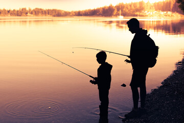 silhouette of father and son fishing on a beautiful lake at sunset 