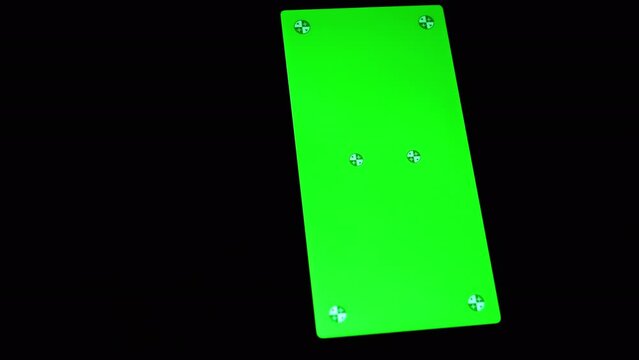 Smartphone with a Green Screen Rotates on a Black Background in the Dark Room. Empty space, a place for text. Markers. Gadget, a mobile phone with a glowing screen. Chrome kay background. Close up.