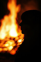 Eine junge Frau steht vor einem großen Feuer