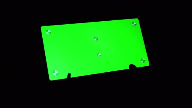 Smartphone with a Green Screen Rotates on a Black Background in the Dark Room. Empty space, a place for text. Markers. Gadget, a mobile phone with a glowing screen. Chrome kay background. Close up.