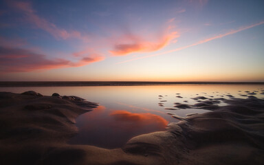 Fototapeta na wymiar Wolken spiegeln sich kurz nach Sonnenuntergang im Wasser