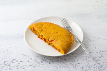 Vegan chickpea omelet with bell peppers on light gray textured background. Healthy homemade food