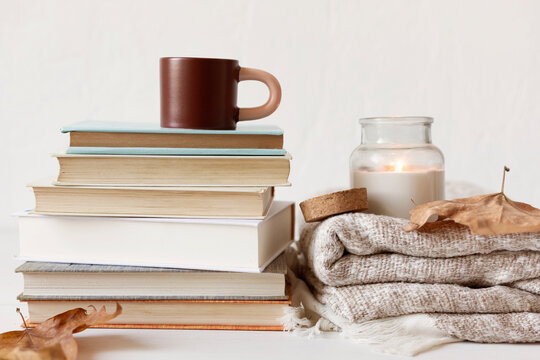 Composition with a stack of books, hot beverage in the mug and warm blanket. Cozy reading scene for cold weather with cup of coffee