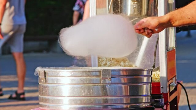 Caucasian Man Perparing Sweet Sugar Candyfloss on Outdoor Stand by Crowded Boulevard