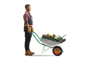 Full length profile shot of a gardener standing with a wheelbarrow full of flowers