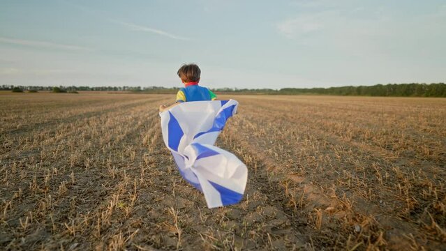 Happy Israeli Jewish little cute boy running with Israel national flag in field
