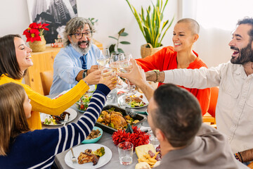 Happy multi generational family toasting white wine at home party celebration. Large group of diverse people celebrating christmas together at home.