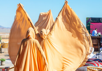 Saudi Arabian women in traditional fully covered golden clothes are dancing on the camel cup race...