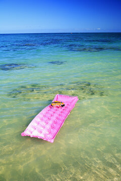Snorkel And Mask Rest On Pink Inflated Raft Afloat On Clear Ocean Water.