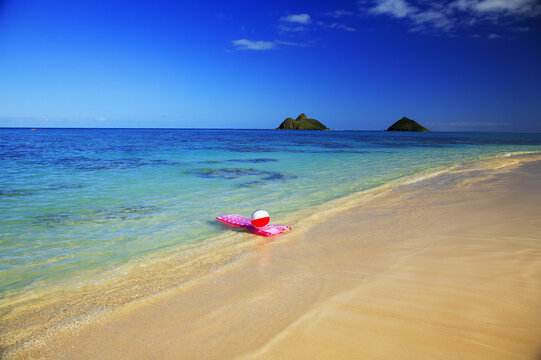 Hawaii, Oahu, Lanikai, Pink Inflated Raft And Beachball On Clear Ocean Water, Mokulua's In Background.