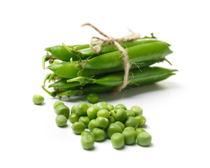Pods of fresh green peas tied with a coarse thread and scattered grains of peas on a white background, close-up.