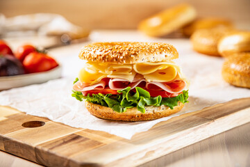 Bagels de pollo asado, pulled pork, jamón , queso, tomate, cebolla roja sobre tabla de madera en mesa de panadería