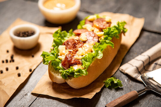 Hot dogs especiales, con pulled pork, bacon, queso fundido, ensalada de col, pepinillo encurtido, cebolla roja, aguacate, ketchup, mayones, salsa picante, coleslaw, sobre pizarra negra y con decoraci&oacute;