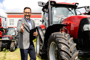 Portrait of professional tractor salesman selling agricultural equipment at dealership.
