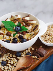 Fruit salad with pine nuts, banana, chocolate and mint in a white plate. advertising photo.top view. Healthy nutritious breakfast.
