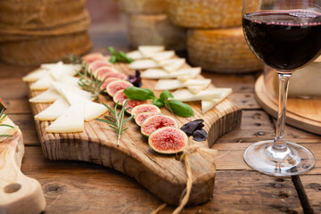 Slices of artisanal goat cheese on wooden boards garnished with fresh ripe figs and fragrant...