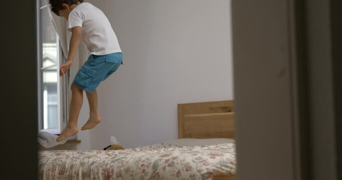 Little boy in pure joy leaping on bed in 1000 fps. Euphoric emotion of child jumping and bouncing in super slow motion