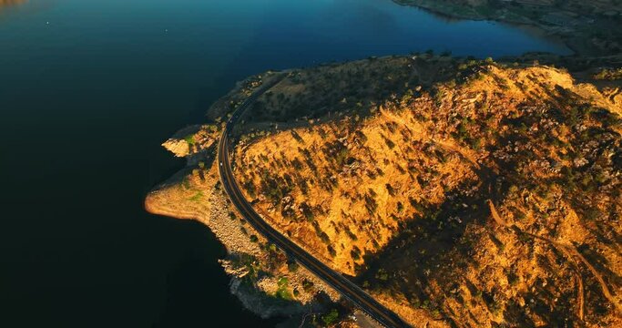 Speed highway circumflexes the mount with rarely growing trees. Beautiful calm lake is at the foot of the mountain. Top view.