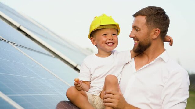 Father and son with hard hats near solar panel, engineering concept