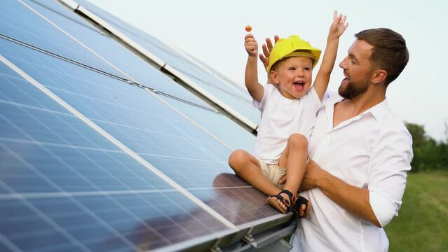 Father and son with hard hats near solar panel, engineering concept