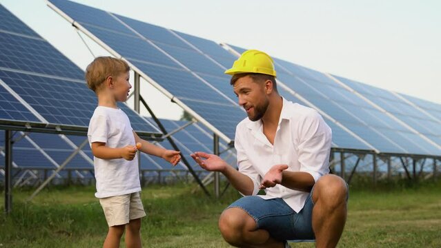 Funny father in a children's helmet and his little son near the solar panels