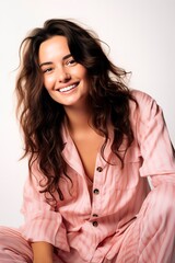 Young natural woman wearing pajamas posing over light background and smiling