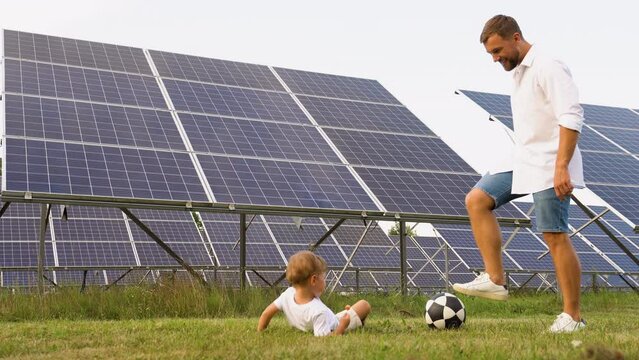 Father and son play football near the solar panels. Father's day