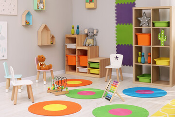 Child`s playroom with different toys and furniture. Cozy kindergarten interior