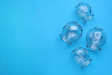 Glass cups on light blue background, flat lay and space for text. Cupping therapy