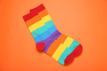 Rainbow socks on orange background, flat lay. LGBT pride