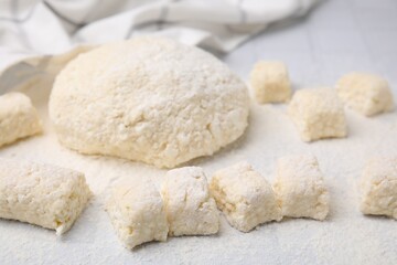 Fototapeta na wymiar Making lazy dumplings. Raw dough and flour on white tiled table, closeup