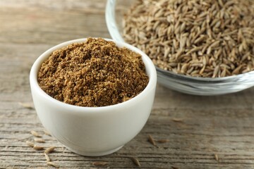 Caraway (Persian cumin) powder and dry seeds on wooden table, closeup