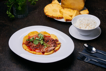 Meat with ananas. Pan-Asian dish setup on the dark table